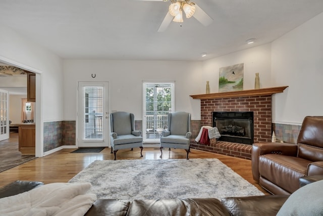 living room featuring a fireplace, light wood-type flooring, and ceiling fan