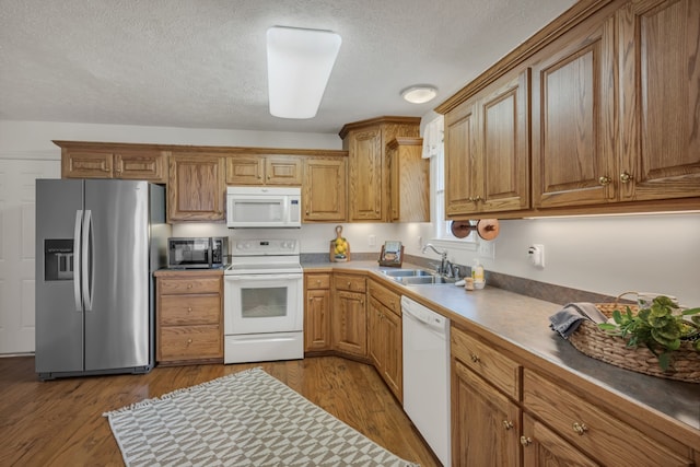 kitchen with a textured ceiling, appliances with stainless steel finishes, sink, and light wood-type flooring