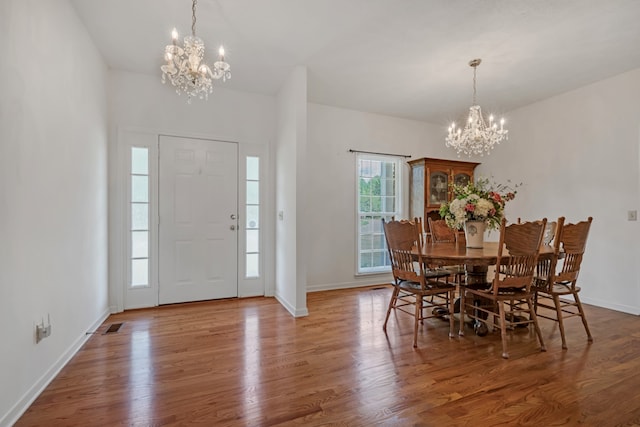 dining area featuring wood-type flooring and an inviting chandelier