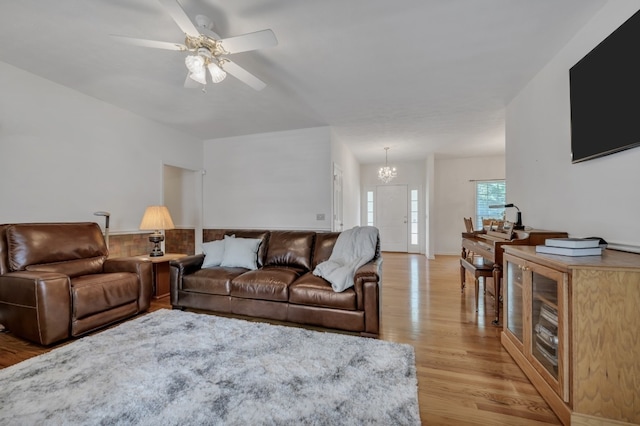 living room featuring ceiling fan with notable chandelier and light wood-type flooring