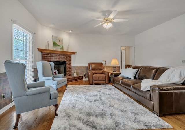 living room featuring a brick fireplace, hardwood / wood-style flooring, and ceiling fan