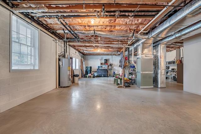 basement with a wealth of natural light, gas water heater, and heating unit