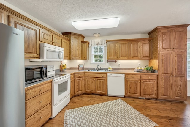 kitchen featuring a textured ceiling, stainless steel appliances, sink, and light wood-type flooring