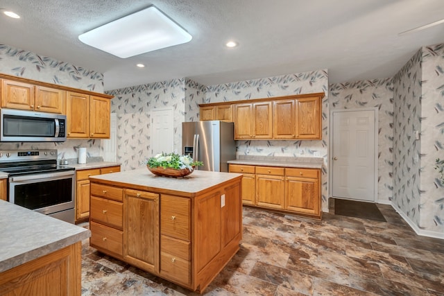 kitchen with a kitchen island, appliances with stainless steel finishes, and a textured ceiling