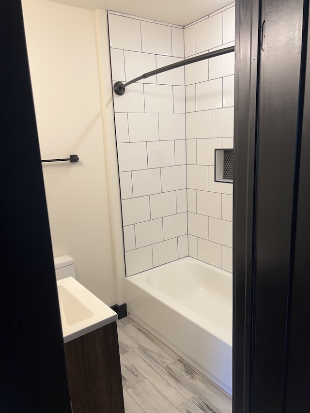 full bathroom featuring vanity, toilet, tiled shower / bath combo, and wood-type flooring