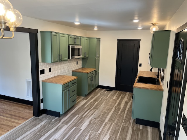 kitchen with wooden counters, wood-type flooring, backsplash, sink, and green cabinetry