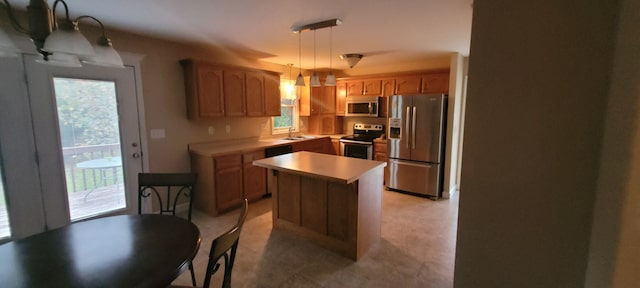 kitchen featuring stainless steel appliances, hanging light fixtures, sink, and a kitchen island