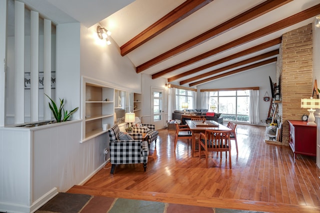 dining room with lofted ceiling with beams, wood-type flooring, and built in shelves