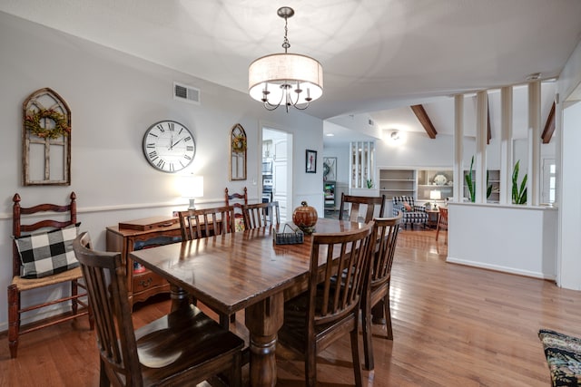 dining space with vaulted ceiling with beams, light hardwood / wood-style floors, and a chandelier