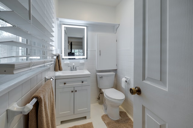 bathroom featuring vanity, tile walls, and toilet