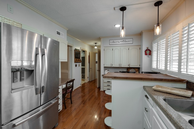 kitchen with hanging light fixtures, wood counters, stainless steel refrigerator with ice dispenser, crown molding, and white cabinets