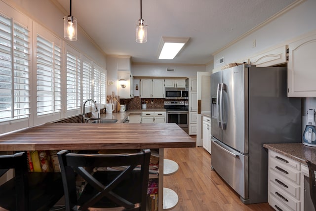 kitchen with decorative light fixtures, decorative backsplash, stainless steel appliances, and wooden counters