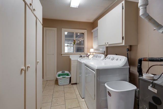 clothes washing area with cabinets, light tile patterned floors, a textured ceiling, and washer and clothes dryer