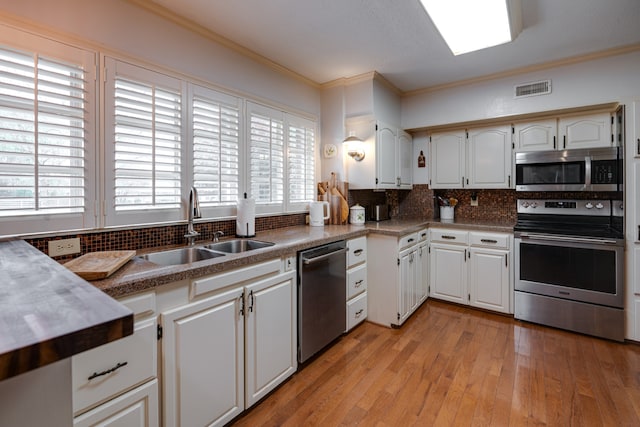 kitchen with backsplash, crown molding, white cabinetry, and stainless steel appliances