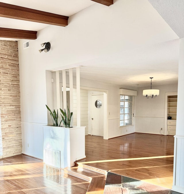 interior space featuring beamed ceiling, wood-type flooring, and a notable chandelier