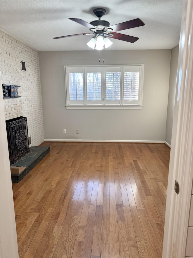 unfurnished living room with a fireplace, hardwood / wood-style floors, a textured ceiling, and ceiling fan