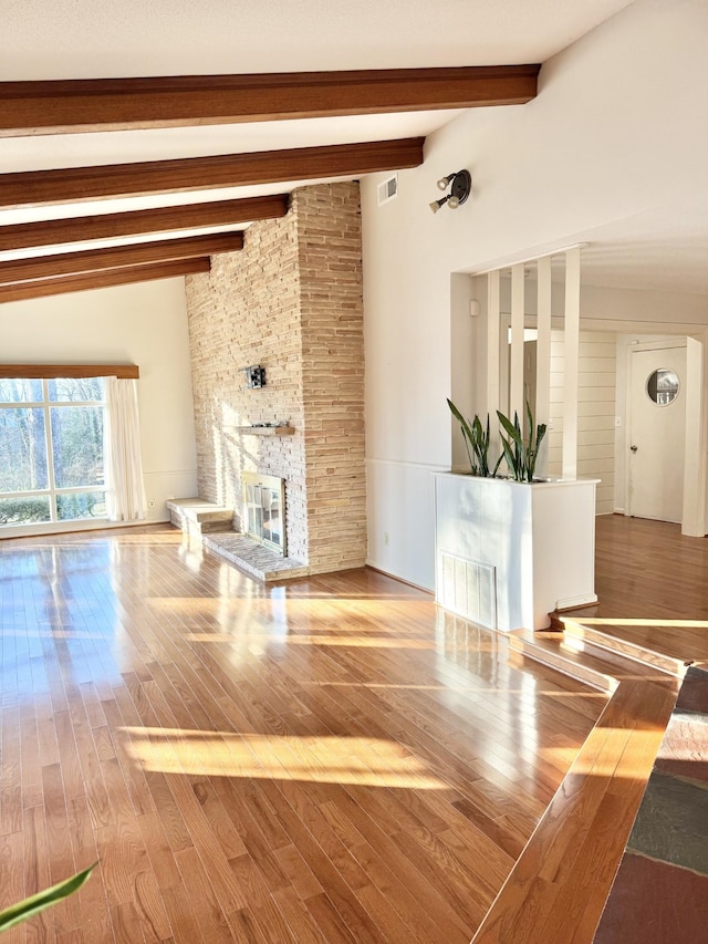 unfurnished living room with a fireplace, hardwood / wood-style floors, and beam ceiling