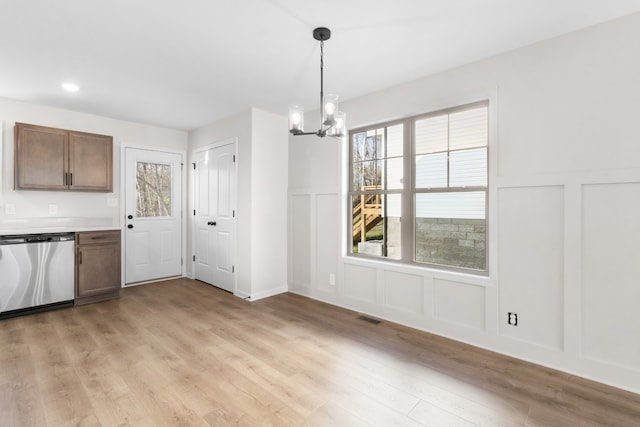 unfurnished dining area featuring an inviting chandelier and light hardwood / wood-style flooring