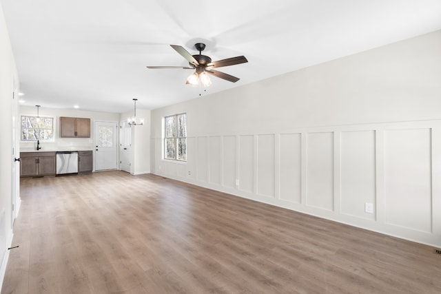 unfurnished living room featuring sink, ceiling fan with notable chandelier, and hardwood / wood-style flooring