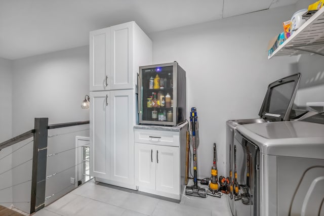 clothes washing area featuring cabinets, washing machine and clothes dryer, and light tile patterned flooring