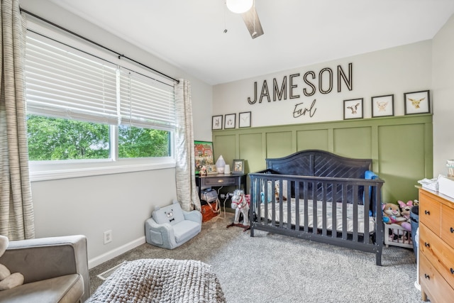 carpeted bedroom with a nursery area and ceiling fan