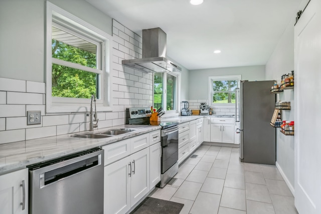 kitchen featuring stainless steel appliances, wall chimney range hood, white cabinetry, and sink