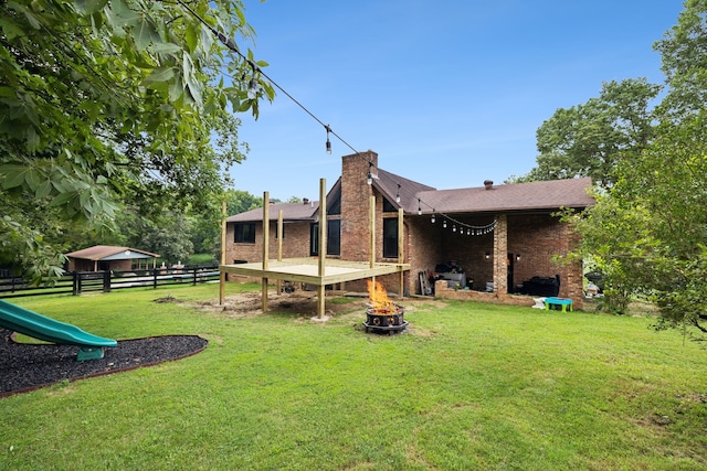 back of property with a playground and a lawn