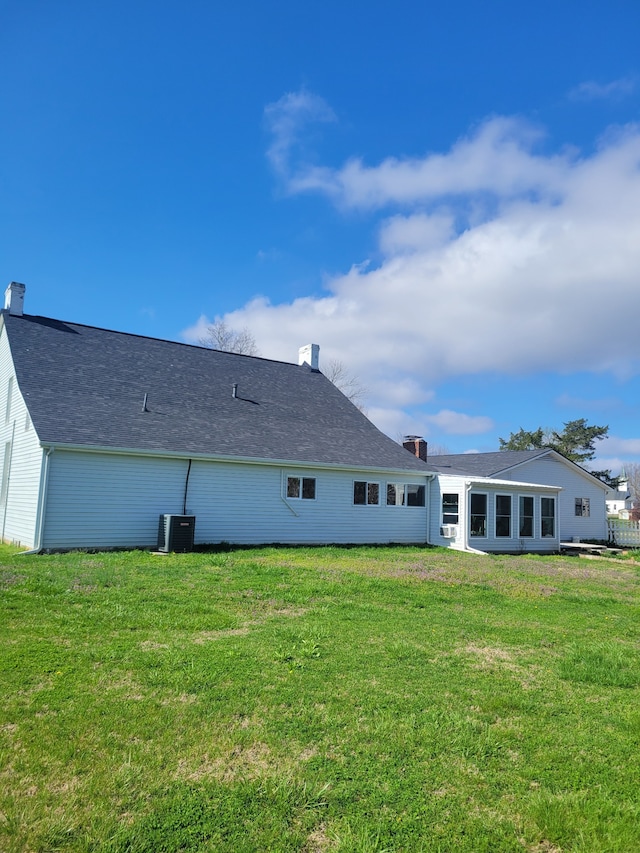 rear view of house with a lawn and central AC unit