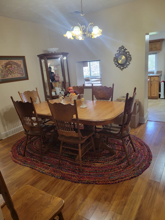 dining area featuring an inviting chandelier, lofted ceiling, and light wood-type flooring