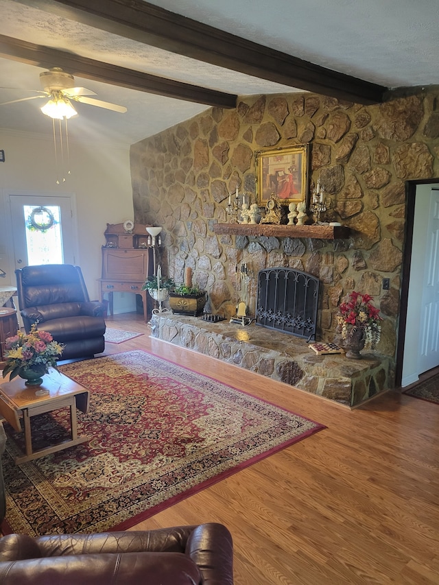 living room with beam ceiling, hardwood / wood-style floors, a fireplace, and ceiling fan