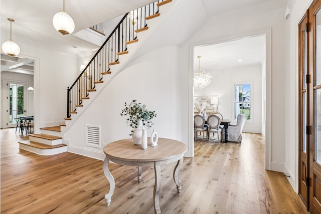 foyer entrance featuring a healthy amount of sunlight, light hardwood / wood-style flooring, and an inviting chandelier