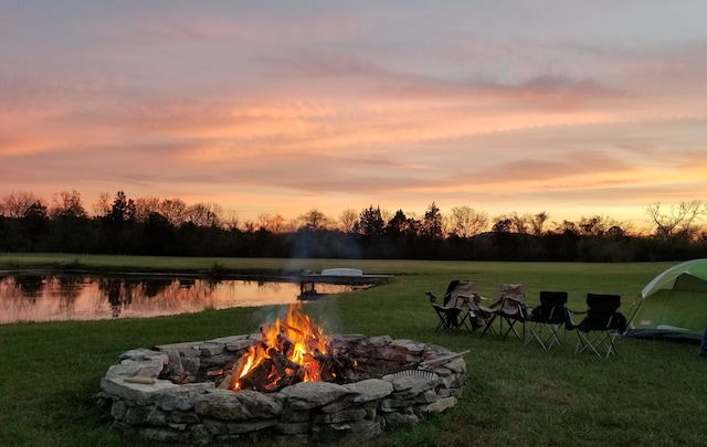 yard at dusk featuring an outdoor fire pit and a water view