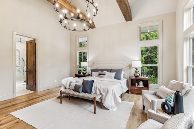 bedroom with beam ceiling, high vaulted ceiling, a chandelier, light wood-type flooring, and ensuite bath