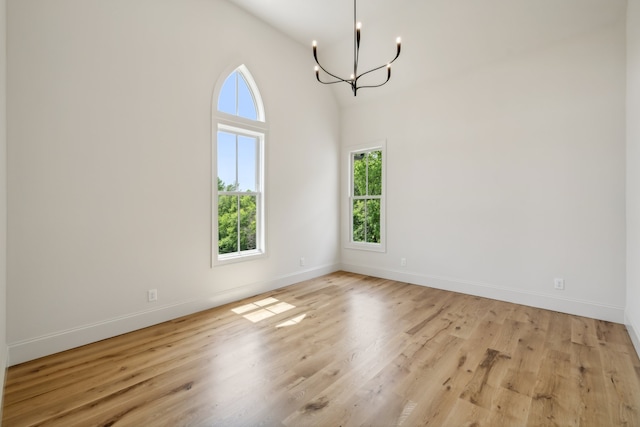 unfurnished dining area featuring a chandelier, light hardwood / wood-style flooring, and high vaulted ceiling