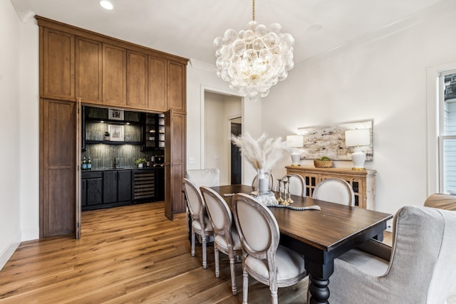 dining space with sink, wine cooler, a notable chandelier, and light hardwood / wood-style flooring