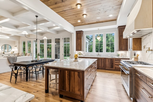 kitchen featuring a kitchen island, high end range, decorative light fixtures, light hardwood / wood-style flooring, and premium range hood