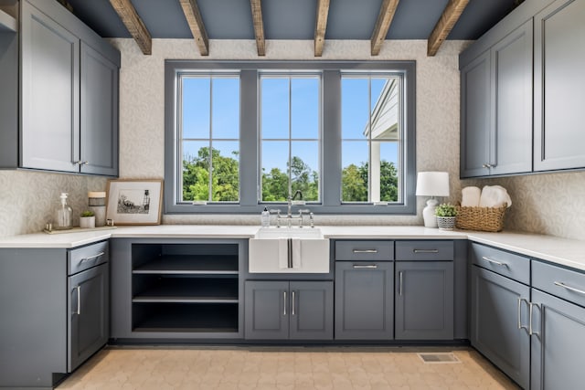 kitchen with gray cabinets, beamed ceiling, sink, and plenty of natural light