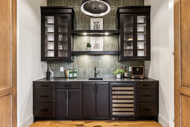 bar featuring light hardwood / wood-style floors, wine cooler, tasteful backsplash, and dark brown cabinets