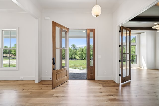 doorway to outside featuring crown molding, french doors, and light wood-type flooring