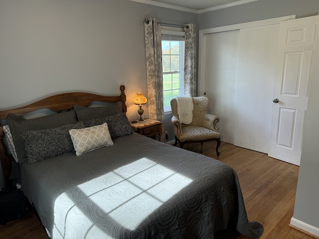 bedroom with crown molding, wood-type flooring, and a closet