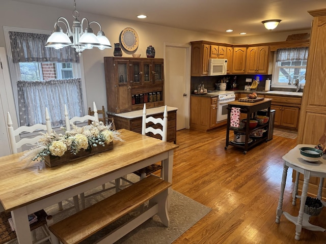 interior space featuring sink, hanging light fixtures, a center island, light hardwood / wood-style floors, and white appliances