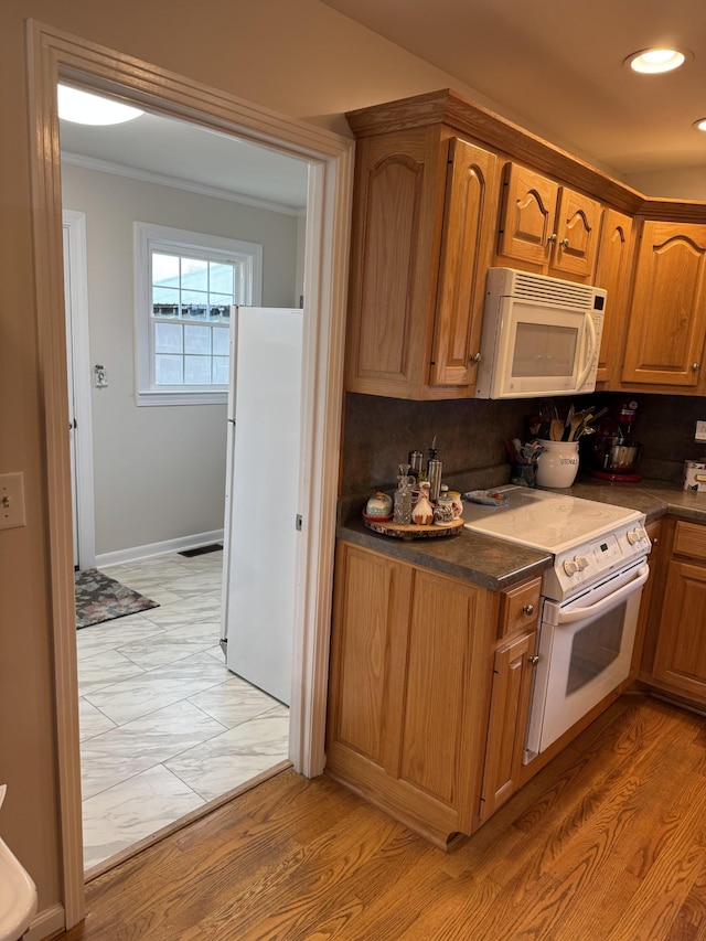 kitchen featuring tasteful backsplash, light wood-type flooring, ornamental molding, white appliances, and dark stone counters