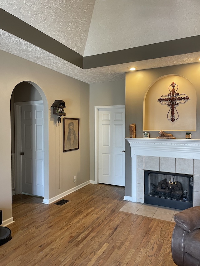 living room with a textured ceiling, a fireplace, and hardwood / wood-style flooring