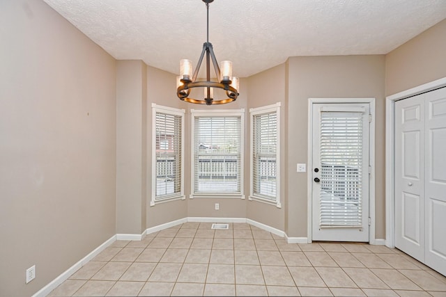 interior space with an inviting chandelier, light tile patterned flooring, and a textured ceiling