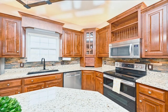 kitchen with appliances with stainless steel finishes, sink, light stone counters, and decorative backsplash