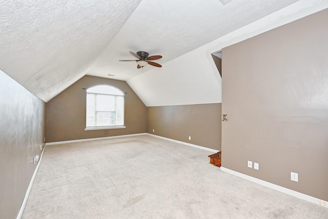 bonus room with ceiling fan, lofted ceiling, light carpet, and a textured ceiling