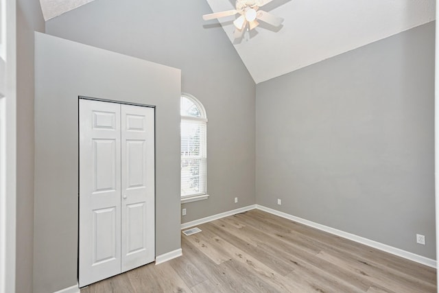 unfurnished bedroom with ceiling fan, high vaulted ceiling, light wood-type flooring, and a closet