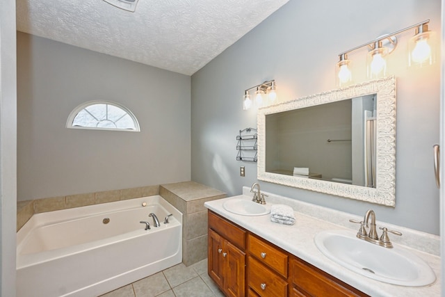 bathroom with tile patterned flooring, vanity, a textured ceiling, and a tub to relax in