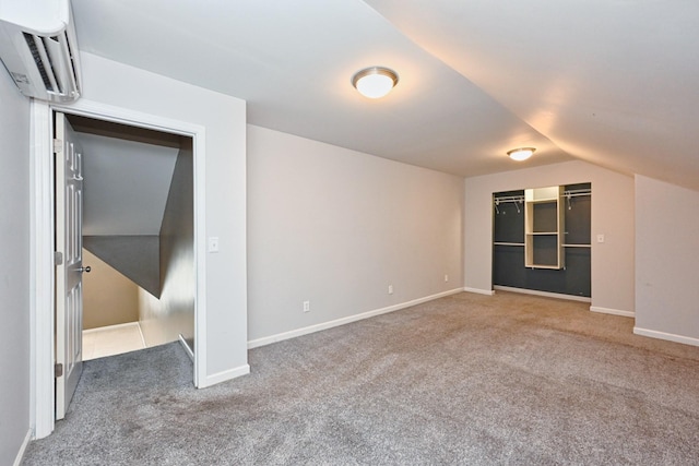 interior space featuring vaulted ceiling, carpet flooring, and a wall mounted air conditioner