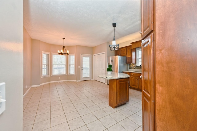 kitchen with a kitchen island, decorative light fixtures, a chandelier, light stone counters, and stainless steel fridge with ice dispenser